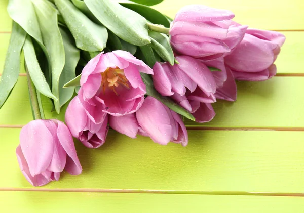 Bellissimo bouquet di tulipani viola su sfondo verde in legno — Foto Stock