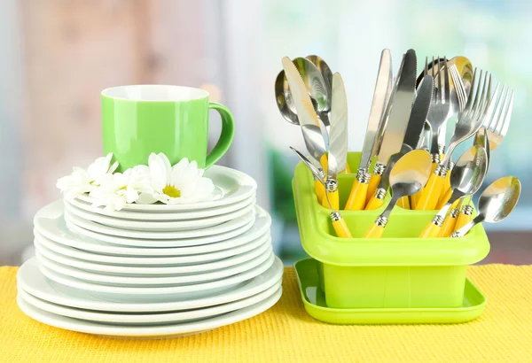 Piatti, forchette, coltelli, cucchiai e altri utensili da cucina su tovagliolo di colore, su sfondo brillante — Foto Stock