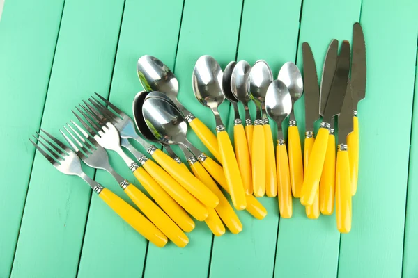 Tenedores, cuchillos, cucharas sobre fondo de madera de color —  Fotos de Stock