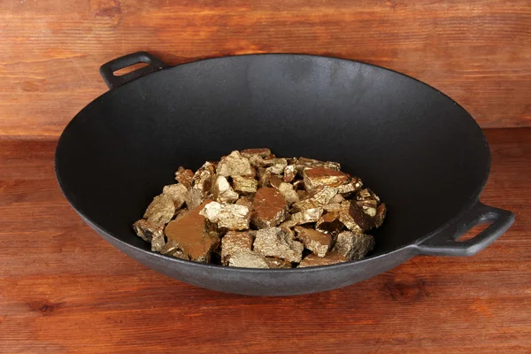 Gold pan with golden nuggets inside on wooden background — Stock Photo, Image