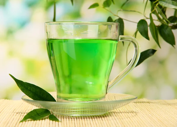 Tasse transparente de thé vert sur tapis de bambou, sur fond de nature — Photo