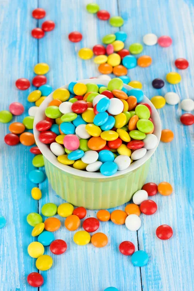 Bunte Bonbons in Schale auf blauem Holzhintergrund — Stockfoto