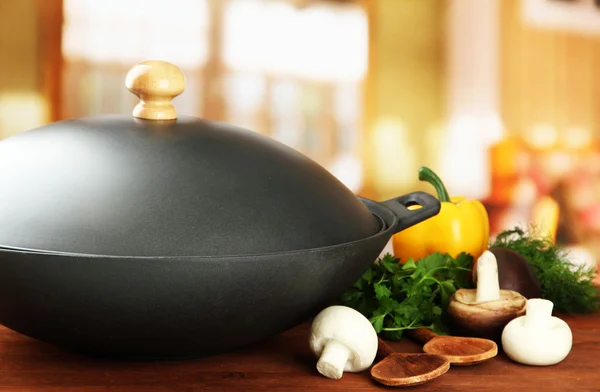 Zwarte wok pan en groenten op houten keukentafel, close-up — Stockfoto