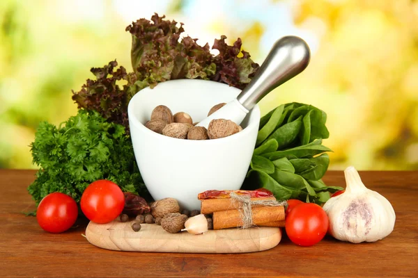 Komposition aus Mörser, Gewürzen, Tomaten und grünen Kräutern, auf hellem Hintergrund — Stockfoto