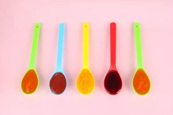 Baby puree in spoons on pink background — Stock Photo, Image