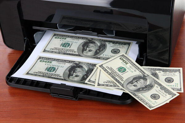 Printer printing fake dollar bills on wooden background