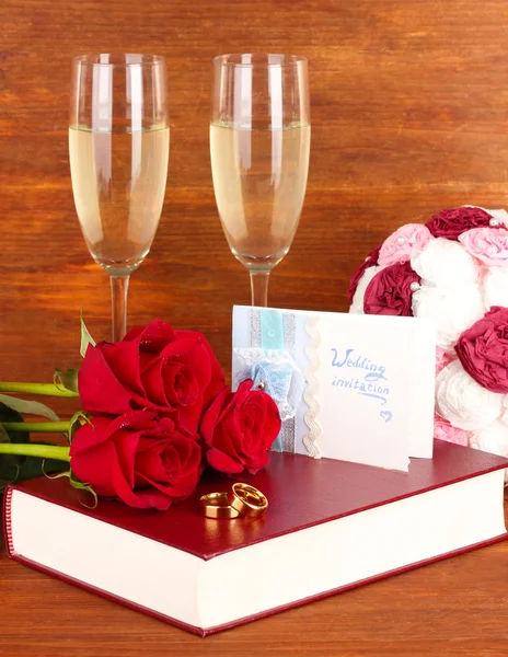 Anillos de boda en la biblia con rosas y copas de champán sobre fondo de madera — Foto de Stock