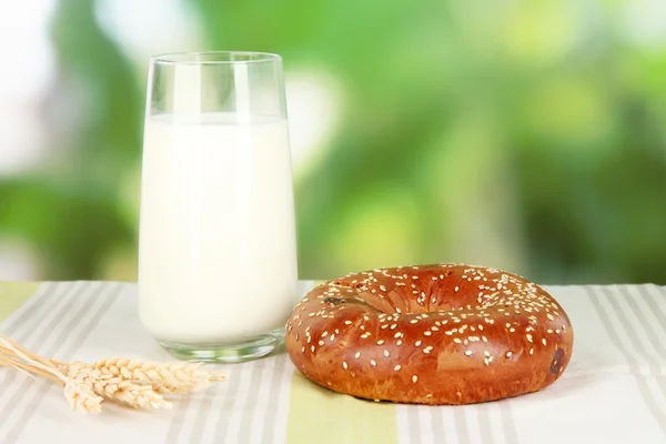 Rotolo di pane e vetro di latte su sfondo naturale — Foto Stock