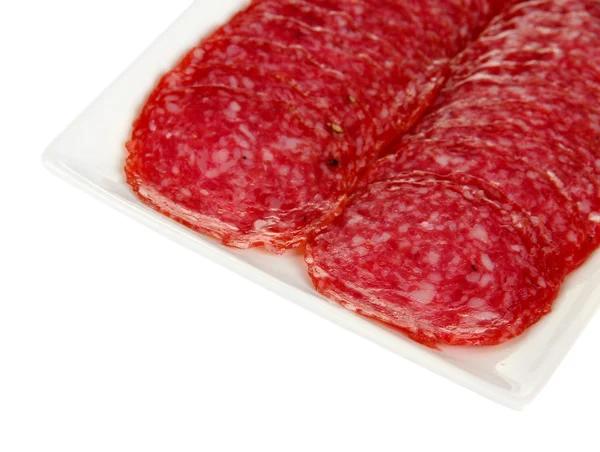 Smakelijke salami op plaat geïsoleerd op wit — Stockfoto