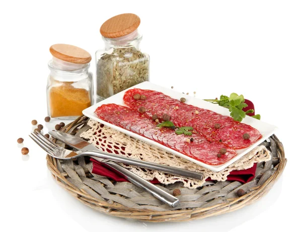 Leckere Salami auf Teller auf Weidenwiege isoliert auf weiß — Stockfoto