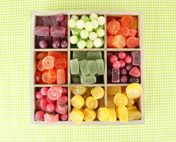 Dulces multicolores en caja de madera, sobre fondo de color — Foto de Stock