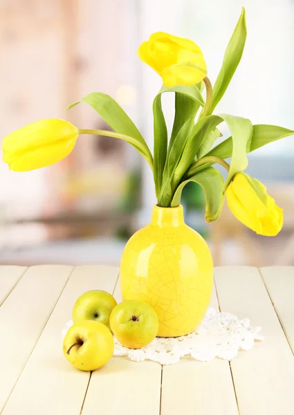 Tulipanes amarillos en jarrón sobre mesa de madera sobre fondo de habitación —  Fotos de Stock