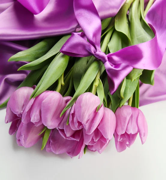 Beautiful bouquet of purple tulips on satin cloth, isolated on white — Stock Photo, Image