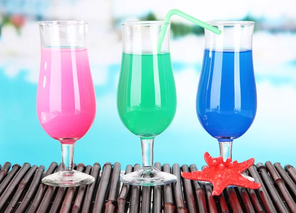 Glasses of cocktails on table near pool — Stock Photo, Image