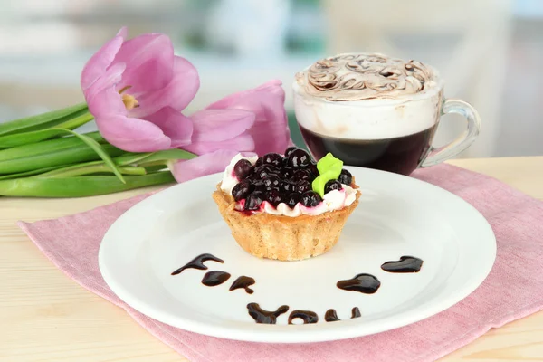 Torta dolce con salsa di more e cioccolato sul piatto, con caffè, su sfondo brillante — Foto Stock