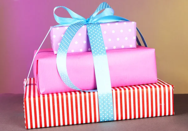 Renkli arka plan üzerinde bir kurdele ile bağlanmış hediye kutusu — Stok fotoğraf
