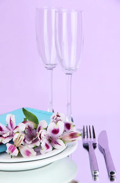 Накрытие праздничного стола с цветами на сиреневом фоне — стоковое фото