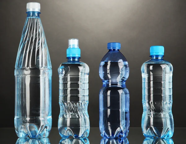 Different water bottles on grey background — Stock Photo, Image