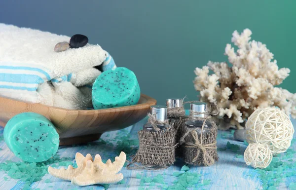 Olio spa, asciugamani candele su tavolo di legno su sfondo blu — Foto Stock