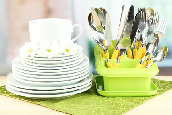 Placas, tenedores, cuchillos, cucharas y otros utensilios de cocina en servilleta de color, sobre fondo brillante — Foto de Stock