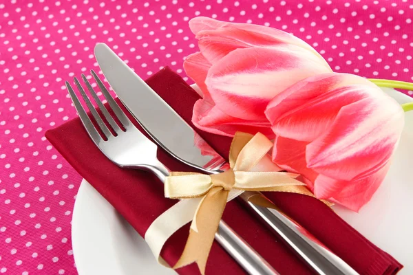Накрытие праздничного обеденного стола с тюльпанами на розовом фоне в горошек — стоковое фото