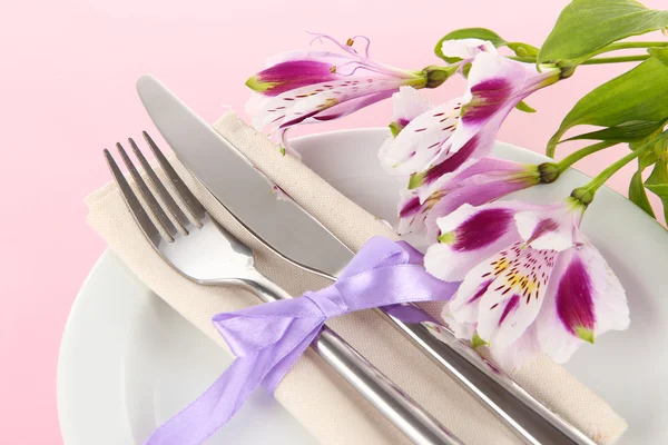 Ünnepi asztal beállítás virágok rózsaszín háttér — Stock Fotó