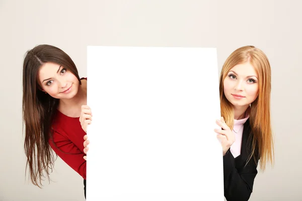 Two business women with blank form on grey background Royalty Free Stock Photos