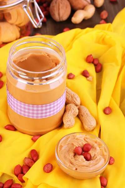 Deliciosa manteiga de amendoim em jarra com cozimento em guardanapo em mesa de madeira close-up — Fotografia de Stock