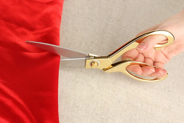 女裁缝师剪红面料米色织物背景上 — 图库照片