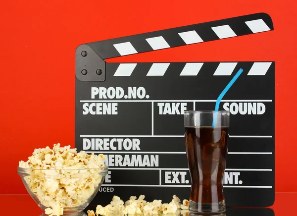 Movie clapperboard, cola and popcorn on red background — Stock Photo, Image