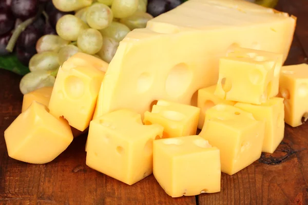 Cut cheese with grape on wooden table — Stock Photo, Image