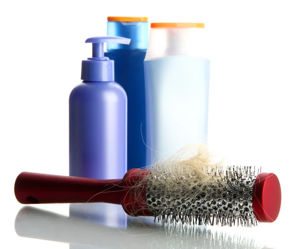 Escova de pente com cabelo perdido e garrafas de cosméticos, isolado em branco — Fotografia de Stock