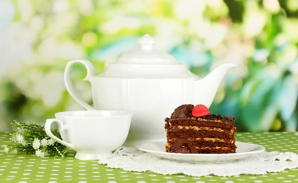 Teapot, cup of tea and delicious cake on natural background — Stock Photo, Image