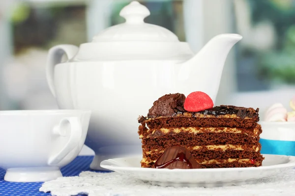 Teekanne, Tasse Tee und leckerer Kuchen auf Fensterhintergrund — Stockfoto