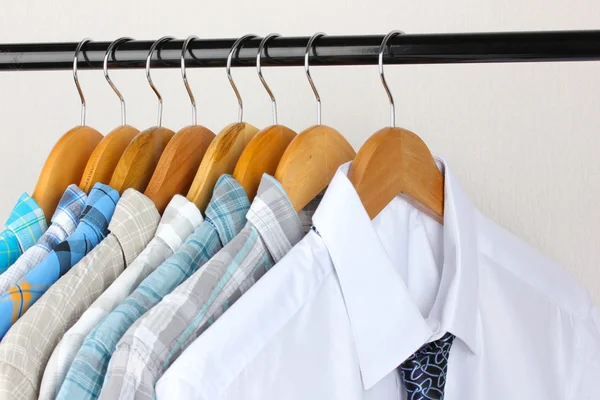 Shirts with ties on wooden hangers on light background — Stock Photo, Image