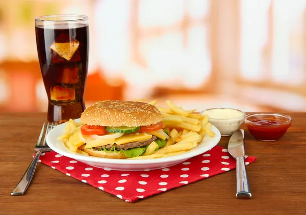 Gustoso cheeseburger con patate fritte e bevanda fredda, su sfondo brillante — Foto Stock