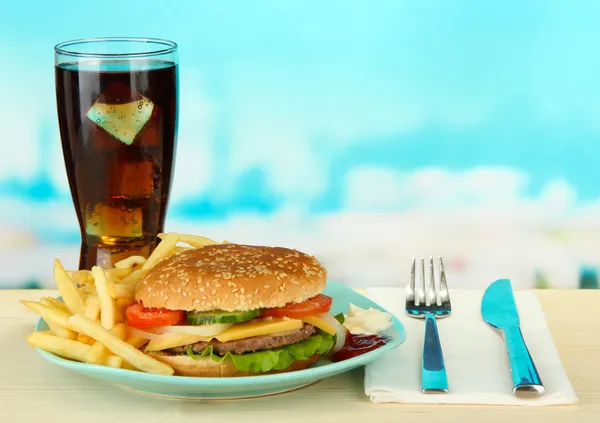 Вкусный чизбургер с жареной картошкой и холодным напитком, на ярком фоне — стоковое фото