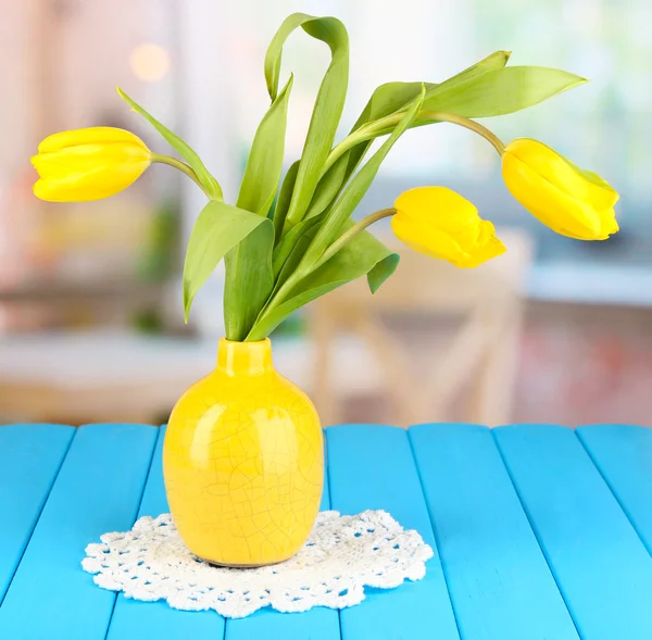 Tulipanes amarillos en jarrón sobre mesa de madera sobre fondo de habitación — Foto de Stock