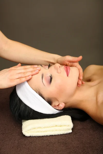 Красивая молодая женщина в спа-салоне принимает массаж головы, на темном фоне — стоковое фото