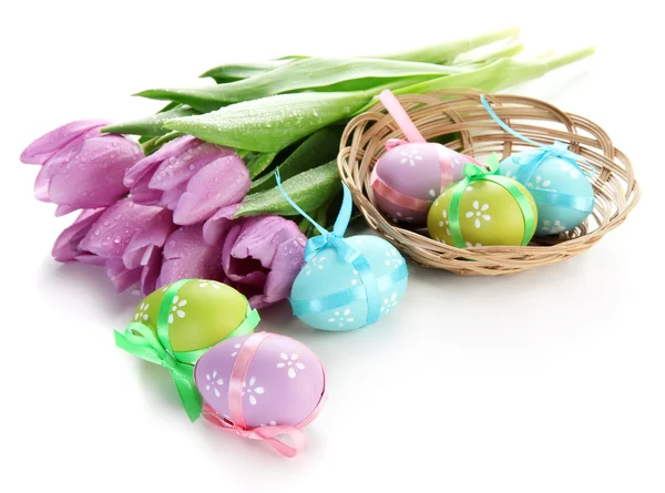 Huevos de Pascua brillantes en cesta y tulipanes, aislados en blanco —  Fotos de Stock