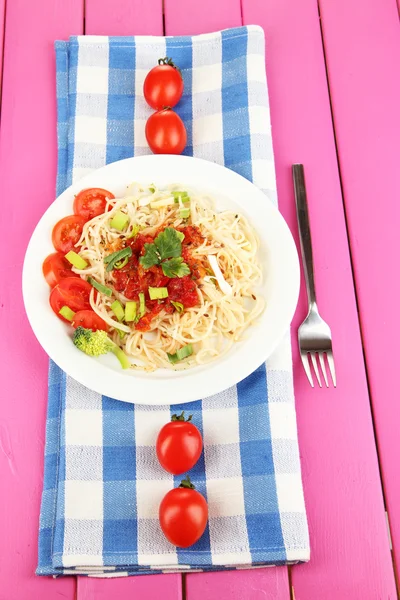 Välsmakande spaghetti med sås och grönsaker på tallriken på träbord närbild — Stockfoto