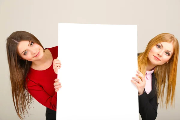 Två affärskvinnor med tomt formulär på grå bakgrund — Stockfoto