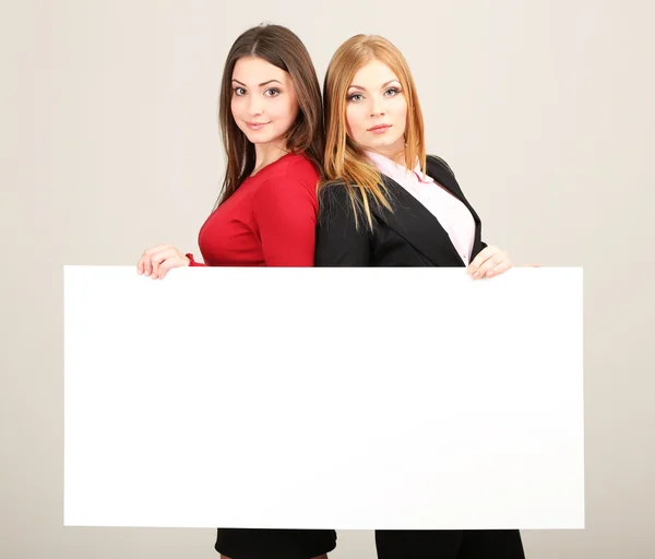 两个商业妇女与灰色的背景上的空白窗体 — 图库照片
