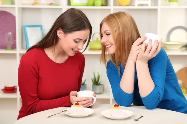 Two girl friends talk and drink tea in kitchen — Stock Photo, Image