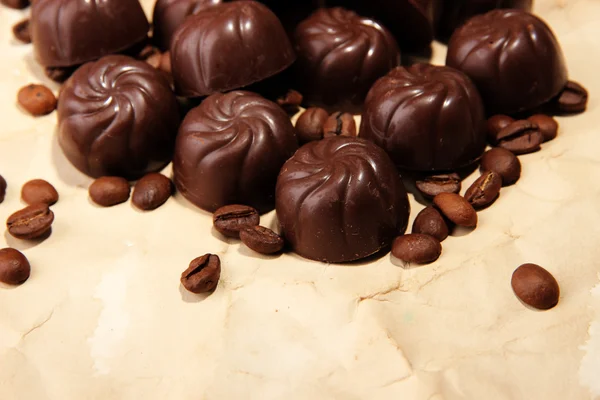 Cukierki czekoladowe i kawa, na tle beżowy papier — Zdjęcie stockowe