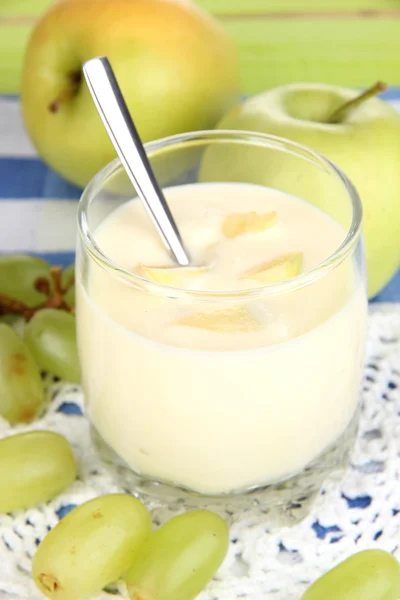 Iogurte delicioso em vidro com frutas na toalha de mesa azul — Fotografia de Stock