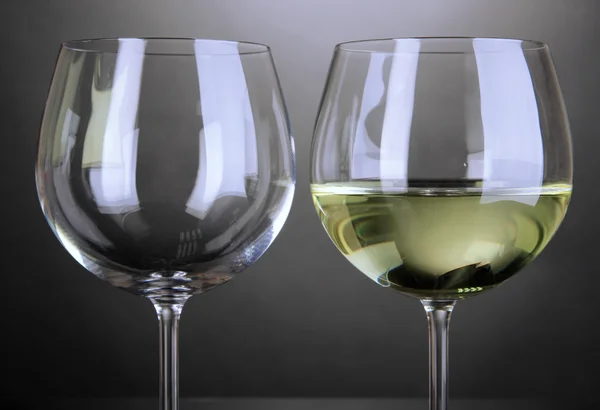 Puste i pełny kieliszek do wina na szarym tle — Zdjęcie stockowe