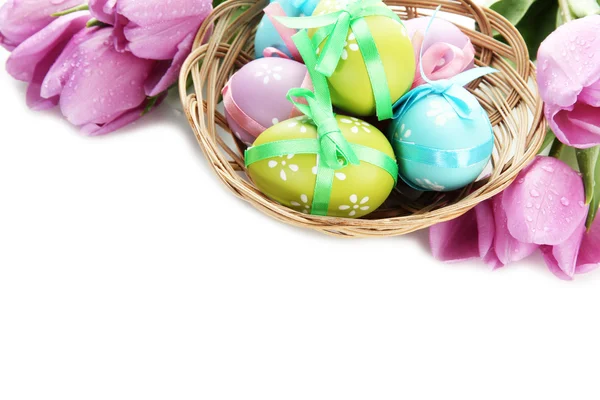 Bright easter eggs in basket and tulips, isolated on white — Stock Photo, Image