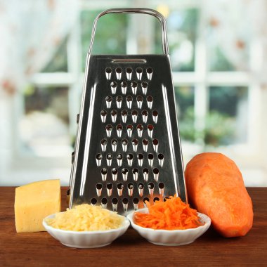 Metal grater and carrot, cheese, on bright background