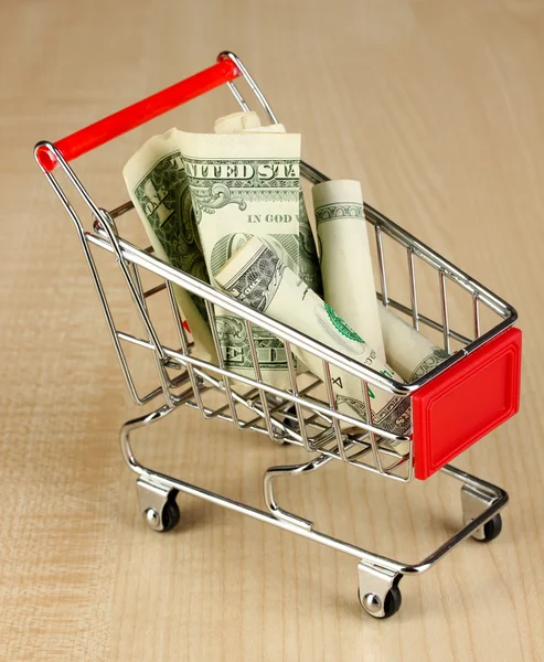 Geld in winkelwagen op houten tafel close-up — Stockfoto